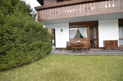 a house with a wooden deck with a table and chairs at Punta Nera: appartamento con giardino e WIFI in Zuel