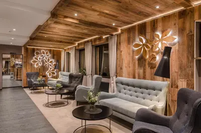 a lobby with couches and chairs and wooden walls at MONDI Hotel Tscherms in Cermes