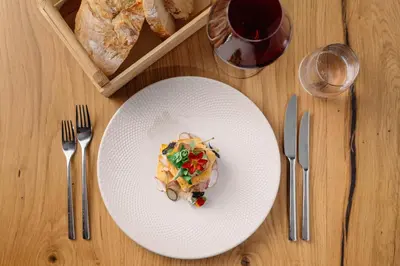 a white plate with food on top of a table at MONDI Hotel Tscherms in Cermes
