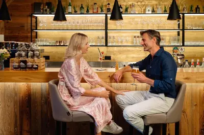 a man and a woman sitting at a bar at MONDI Hotel Tscherms in Cermes