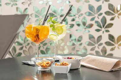 two wine glasses sitting on a table with snacks at MONDI Hotel Tscherms in Cermes
