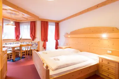 a bedroom with a large bed and a table at Chalet Hotel Diamant in San Martino in Badia