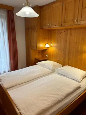 a large bed in a room with wooden walls at Chalet Hotel Diamant in San Martino in Badia