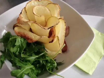 a white plate with a sandwich and greens on it at Chalet Hotel Diamant in San Martino in Badia