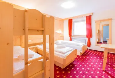 a room with three bunk beds and a desk at Chalet Hotel Diamant in San Martino in Badia