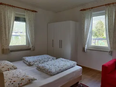two beds in a bedroom with two windows at Hirschenhof in Laives