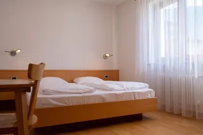 a bedroom with a bed and a window with white curtains at Rabland Haus Texel I in Parcines