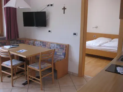 a room with a table and a bed and a cross on the wall at Ferienwohnung im Haus Texel IV in Parcines