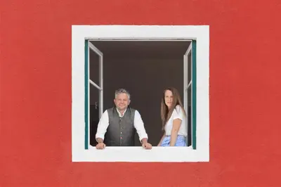 a man and a woman looking out of a window at Casa al Sole in Ortisei