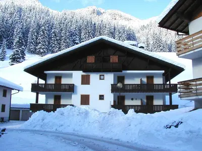 a house covered in snow in front of a mountain at Solaia in Mazzin