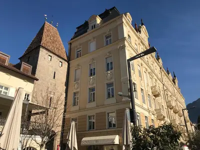 a building with a tower next to a castle at Ladurner Suites in Merano