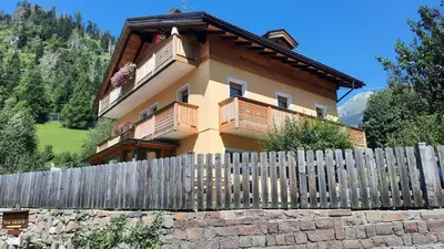 a house covered in snow next to a fence at B&BeautyFol Dolomites B&B adults only in Predazzo