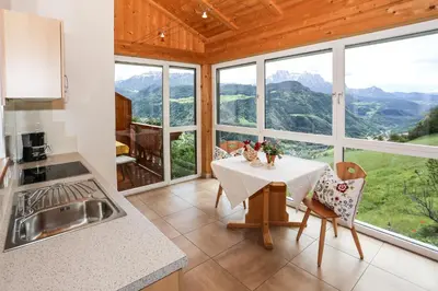 a kitchen and dining room with a table and some windows at Oberpalwitterhof in Barbiano