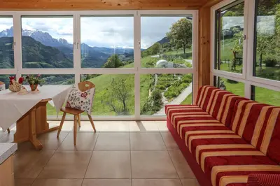 a living room with a table and chairs and large windows at Oberpalwitterhof in Barbiano