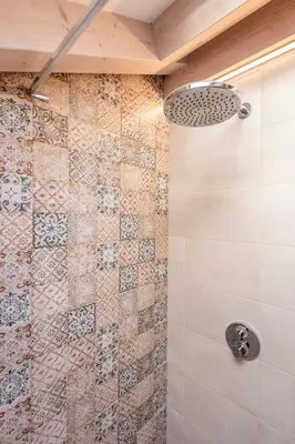 a bathroom with a shower with a tiled wall at Sweet Dolomites Sauna & Jacuzzi in Agordo