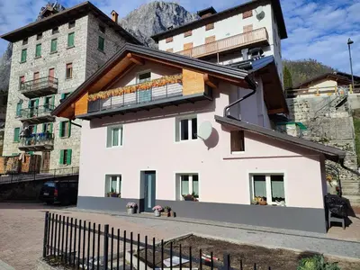 a white building with a balcony on top of it at Sweet Dolomites Sauna & Jacuzzi in Agordo