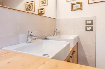 a bathroom with two sinks and a mirror at Sweet Dolomites Sauna & Jacuzzi in Agordo