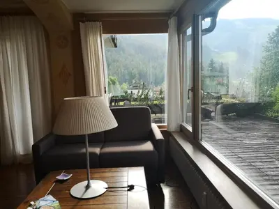 a living room with a chair and a large window at Ciasa Pascal in San Vigilio