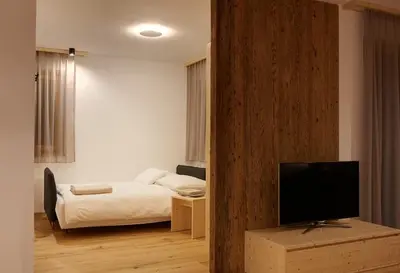 a bedroom with a bed and a flat screen tv at Ariala - Mountain Holiday Home in Falzes