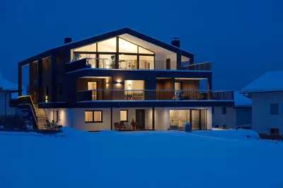 a large building with a lot of windows at night at Ariala - Mountain Holiday Home in Falzes