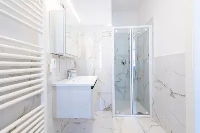 a white bathroom with a shower and a sink at Lara's Guesthouse in Merano
