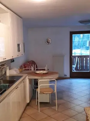 a kitchen with a counter and a table with a chair at Le betulle in Predazzo