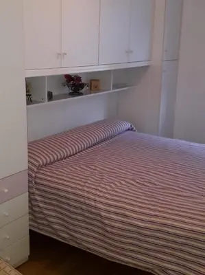 a bed in a bedroom with white cabinets at Le betulle in Predazzo
