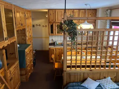 a kitchen with wooden cabinets and a bed in a room at Mellon House in Falcade
