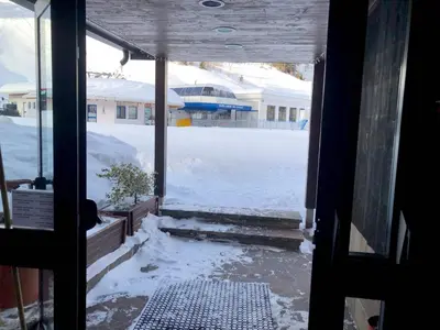 a view of a snow covered yard through a door at Mellon House in Falcade