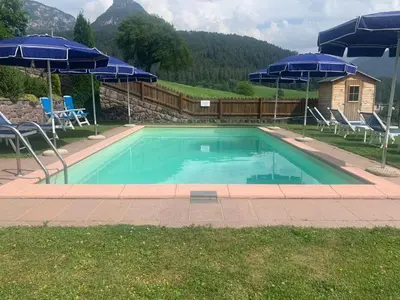 a swimming pool with blue umbrellas and chairs at App. Eichenheim in Fiè