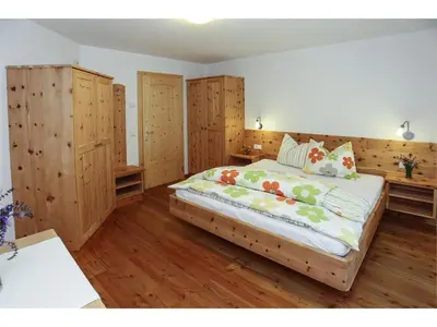 a bedroom with a large bed with wooden floors and wooden cabinets at Bio Kräuterhof Oberpalwitter in Barbiano