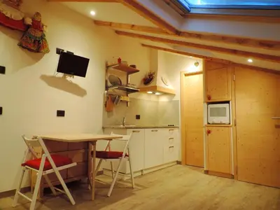 a kitchen with a table and chairs in a room at incantevole mansarda in val di Fassa in Alba di Canazei