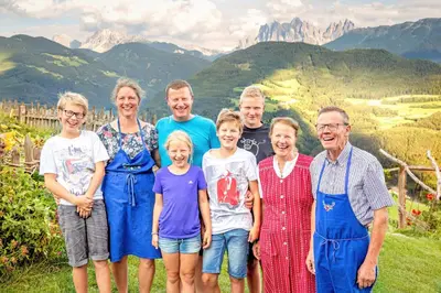a family posing for a picture with mountains in the background at Oberhauser Hof - Apartments in Feldthurns