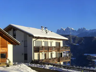a house with snow on the roof with mountains in the background at Oberhauser Hof - Apartments in Feldthurns