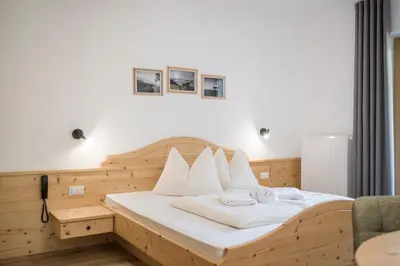 a bedroom with a wooden bed with white pillows at Pension-Appartement Mitterhofer in Schenna