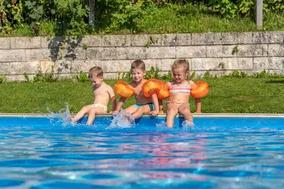 three children in the water in a swimming pool at Pension-Appartement Mitterhofer in Schenna