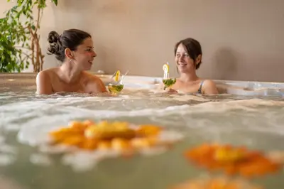 two women sitting in a hot tub with drinks at Pension-Appartement Mitterhofer in Schenna