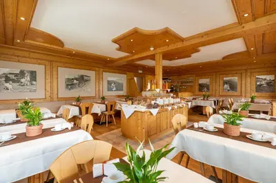 a restaurant with white tables and chairs and wooden walls at Pension-Appartement Mitterhofer in Schenna