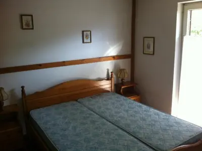 a bedroom with a bed with a blue comforter and a window at Casa Cavalese sul Cermis in Cavalese