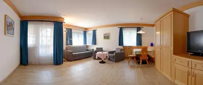a living room with a couch and a table and a television at Casa Roder by Garni Snaltnerhof in Ortisei