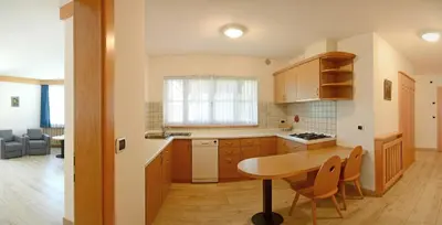 a kitchen with a wooden table and a dining room at Casa Roder by Garni Snaltnerhof in Ortisei