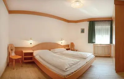 a bedroom with a bed and a table and a window at Casa Roder by Garni Snaltnerhof in Ortisei
