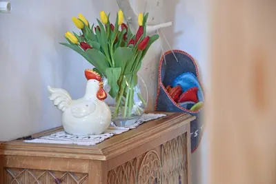 a table with a vase of flowers and a chicken on it at Ebenhof in Collepietra