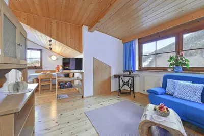 a living room with a blue couch and a kitchen at Ebenhof in Collepietra