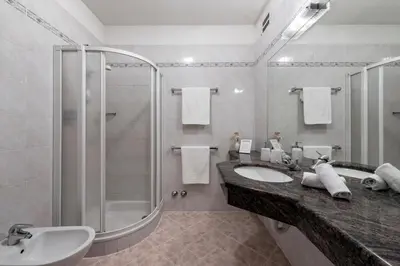 a white bathroom with a sink and a shower at Baumannhof in Schenna