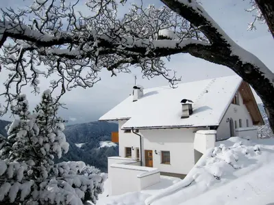 a house covered in snow in the mountains at Appartment Kircherhof in Laion
