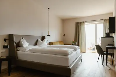 a bedroom with two beds and a desk and a window at Ansitz am Eck by Hotel Pernhof in Termeno