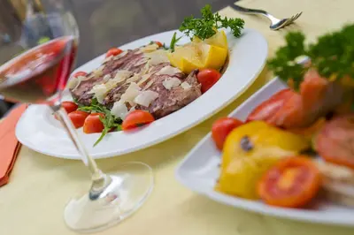 two plates of food and a glass of wine on a table at Ansitz am Eck by Hotel Pernhof in Termeno