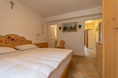 a bedroom with a large white bed and a hallway at Casa Rosi in Pozza di Fassa