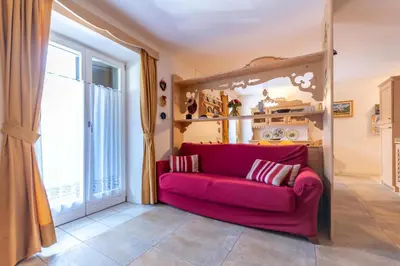 a red couch in a room with a large window at Casa Rosi in Pozza di Fassa